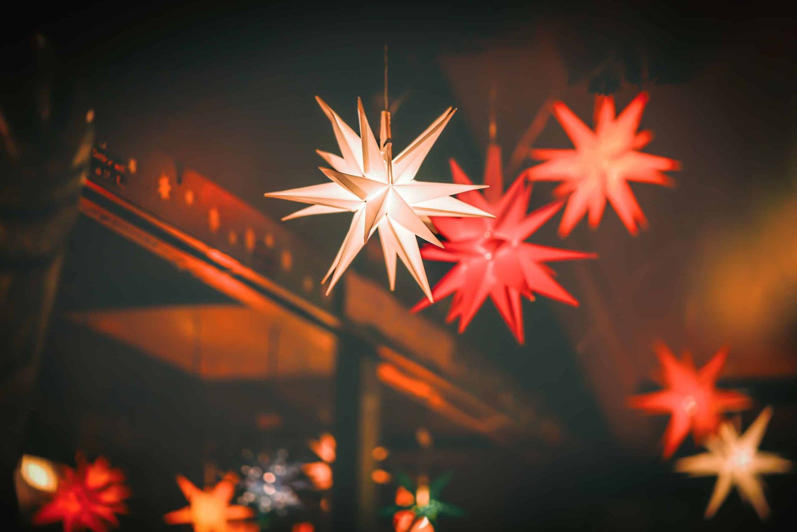 Glowing red, white, and orange star-shaped holiday lights illuminate a dark nighttime scene.