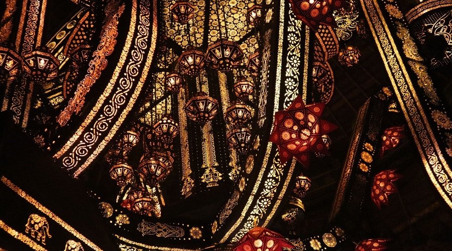 Ornate black fabric with gold embroidery and red jeweled accents.