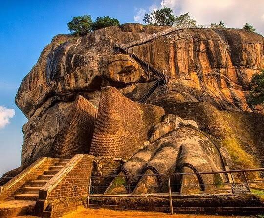 Ancient Sigiriya lion paws and brick staircase beneath Sri Lanka’s towering rock fortress.