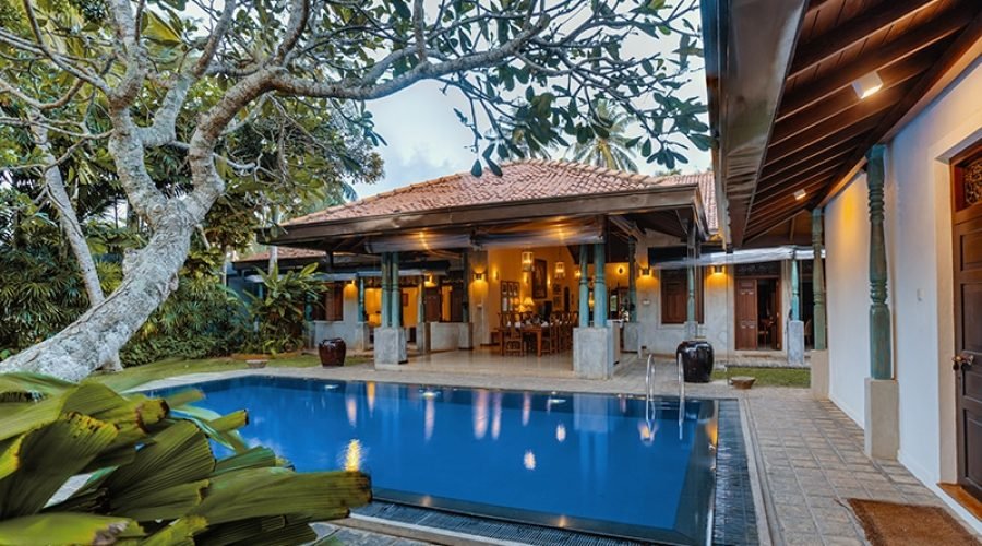 Tropical villa pool courtyard with lush gardens and illuminated pavilion in Bentota, Sri Lanka.