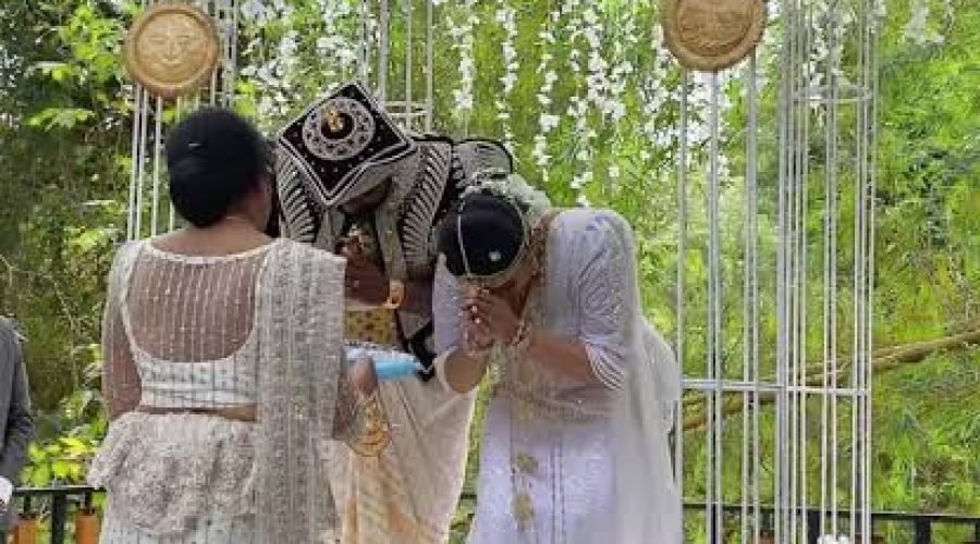 Bride and groom kiss beneath a floral canopy at an intimate garden wedding ceremony.