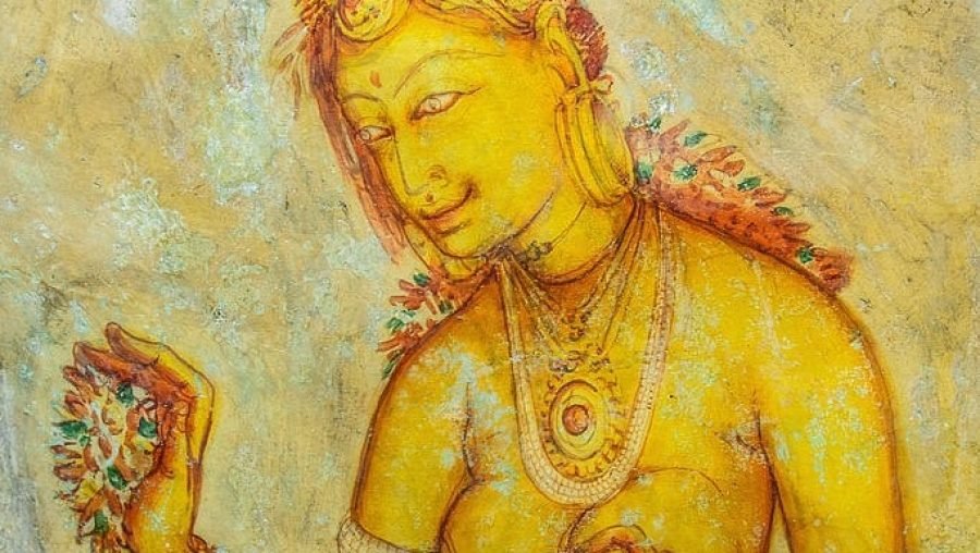 Golden South Asian goddess in ornate jewelry against a textured temple mural background.