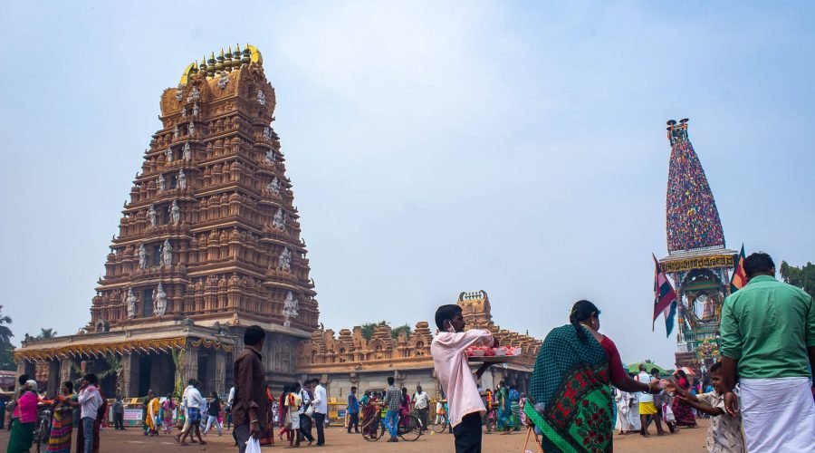 Grand Gopuram at a Bustling Hindu Temple Complex Visitors gather beneath ornate gopurams in a grand Hindu temple courtyard.