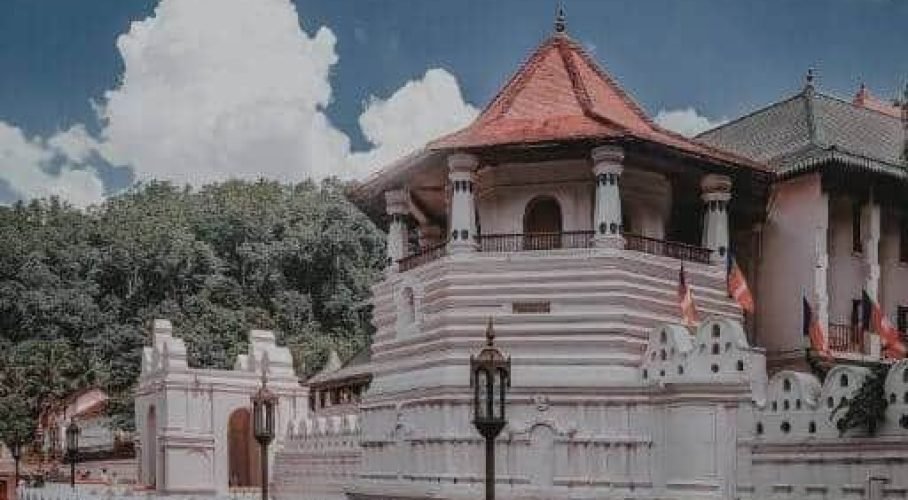 Ornate historic temple complex with striped pavilion beneath a dramatic blue sky.