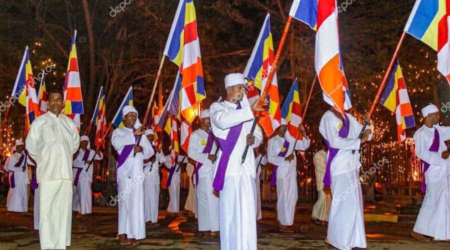 Buddhist flag bearers in white robes join Kandy Perahera night procession in Sri Lanka.