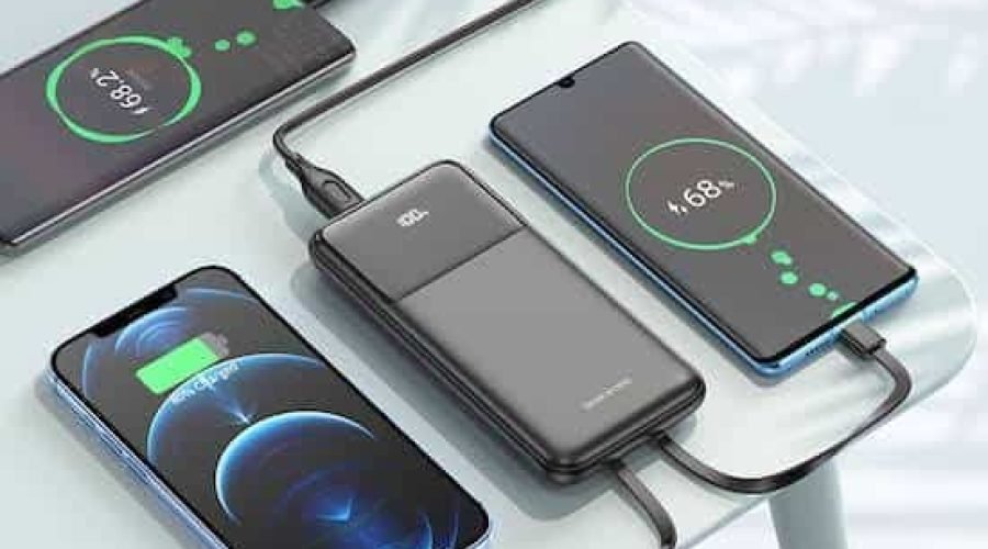 Multi-device charging station powering smartphones with a portable power bank on a glass table.