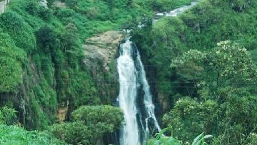 Tropical waterfall cascading down a rocky cliff into a lush green ravine.