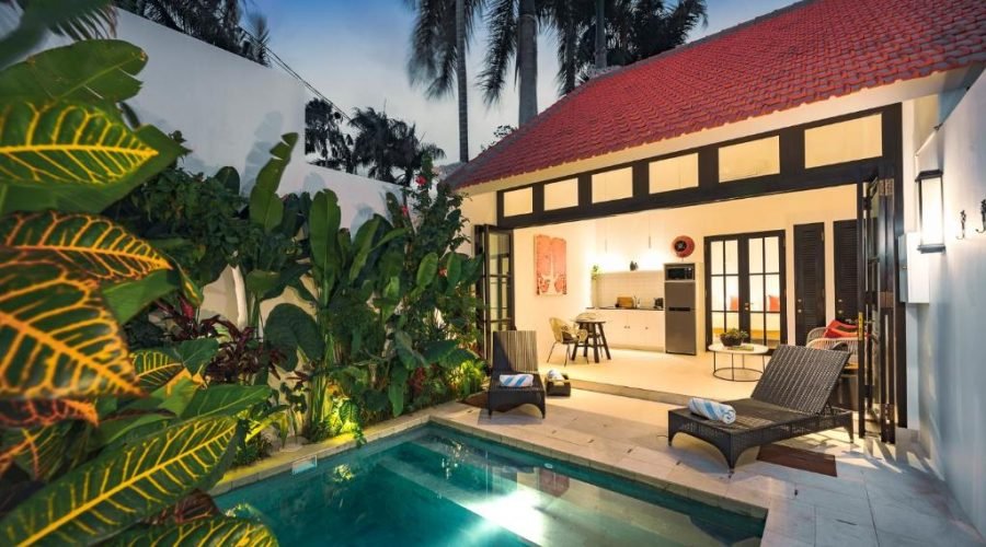 Tropical villa pool at dusk surrounded by lush greenery and warm resort lighting.