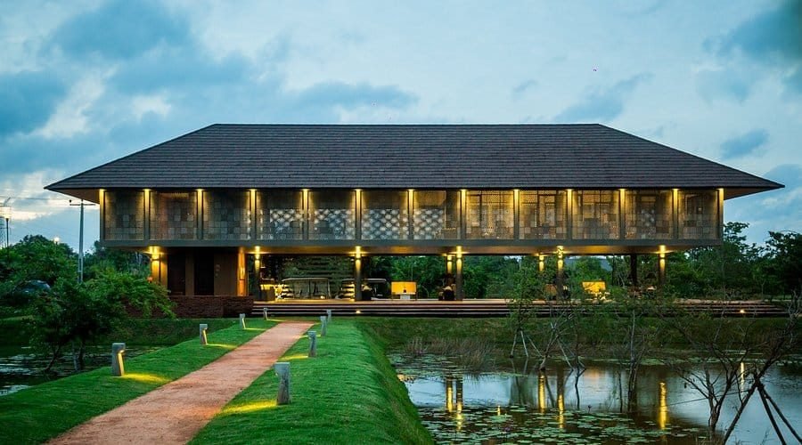 Water Garden Sigiriya resort pavilion glowing beside a reflective pond at dusk.