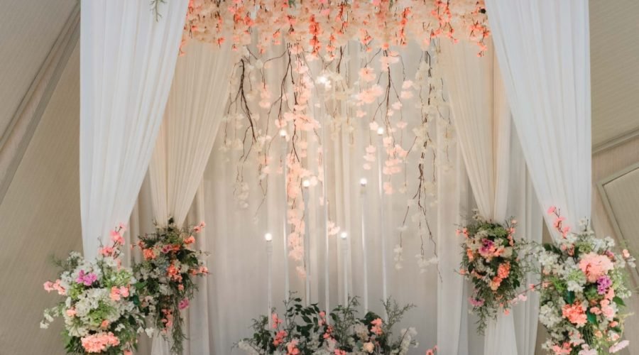 Elegant Sri Lankan wedding poruwa with pastel flowers, crystal garlands, and warm lights.